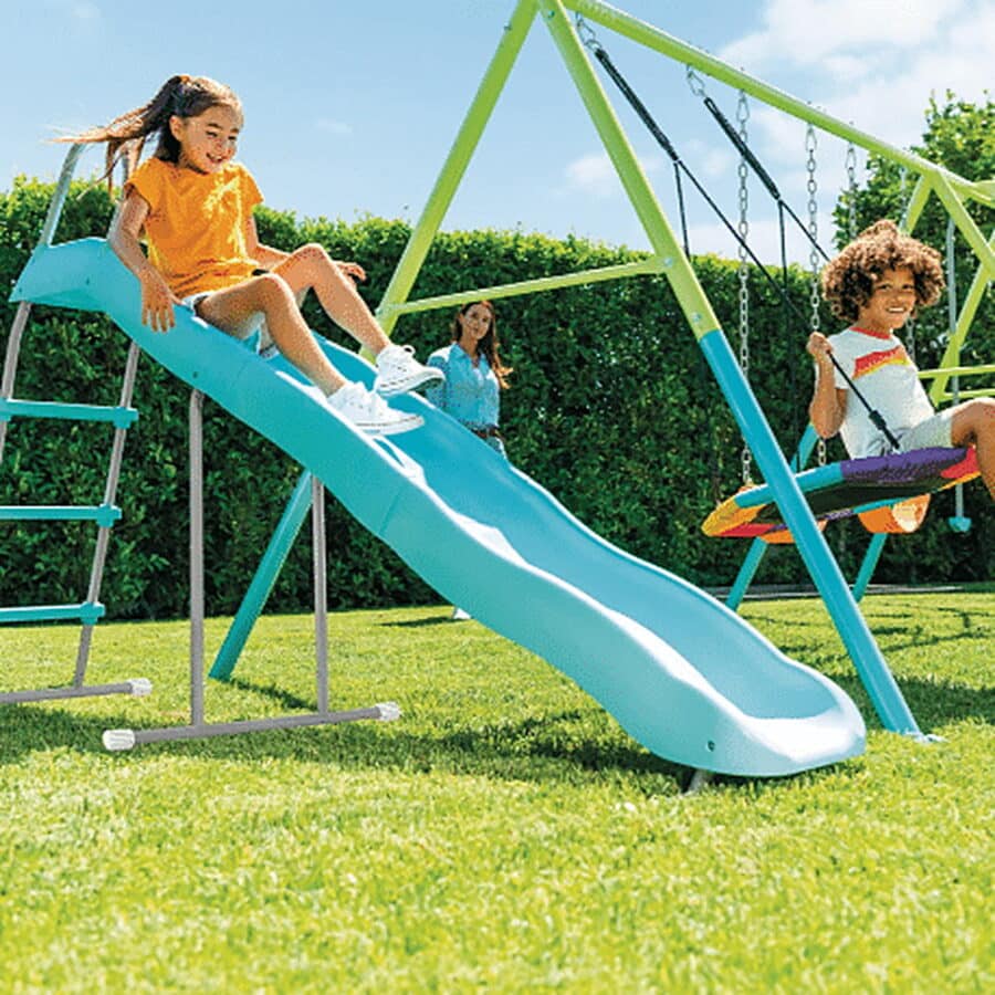 שלושה ילדים משחקים על סט לחצר עם מגלשה ונדנדות על דשא | yrz