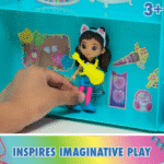 בובת גבי עם גיטרה בתוך חדר משחקים צבעוני, יד מחזיקה את הבובה | yrz