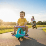 ילד רוכב על בימבה תכלת וסגול על שביל בפארק, וברקע עגלה עם מבוגר