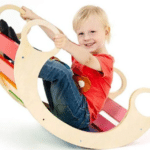 ילד יושב על נדנדת עץ צבעונית בצורת סהר עם ידיות | yrz