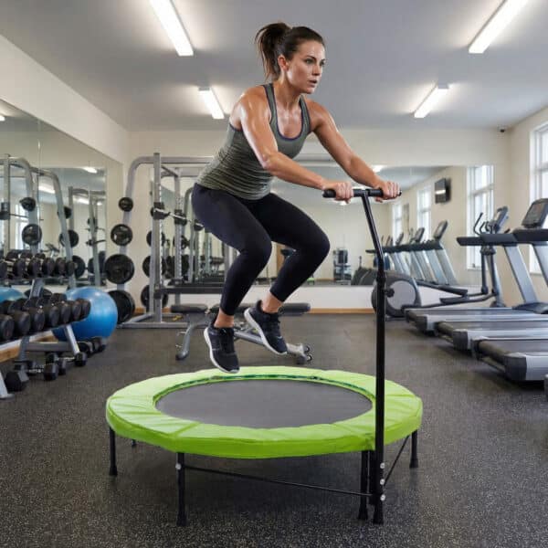 אישה קופצת על טרמפולינת ספורט ירוקה בחדר כושר | yrz טרמפולינות