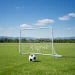 שער כדורגל ממתכת עם רשת על דשא, עם כדורגל בקדמת התמונה | yrz
