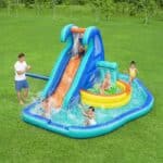 ילדים משחקים בפארק מים מתנפח עם מגלשה ובריכת שכשוך על דשא | yrz