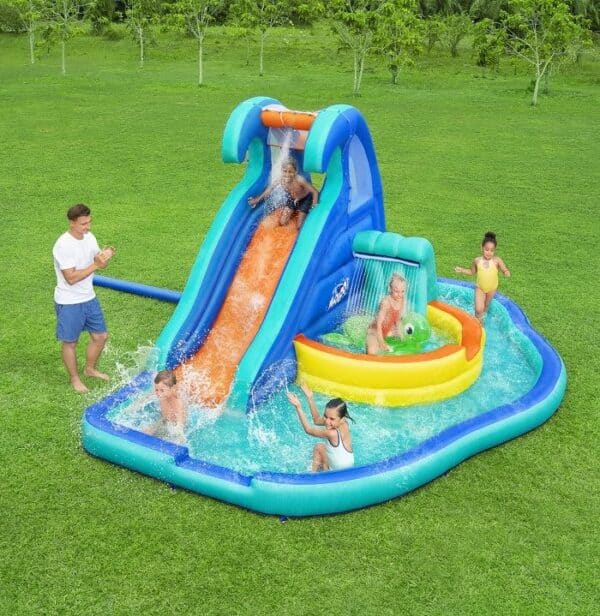 ילדים משחקים בפארק מים מתנפח עם מגלשה ובריכת שכשוך על דשא | yrz
